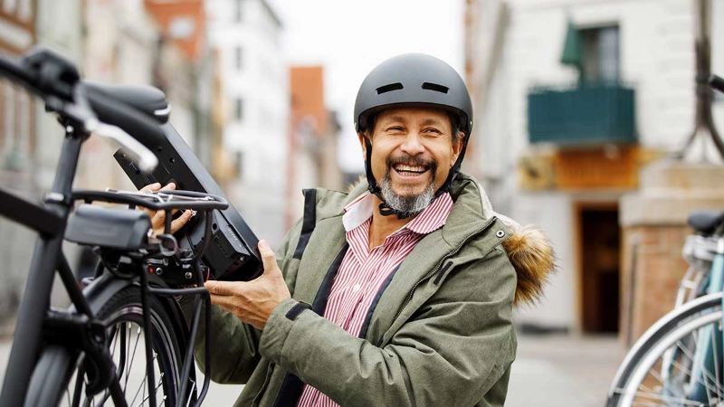 Ein lachender Mann neben seinem S-Pedelec