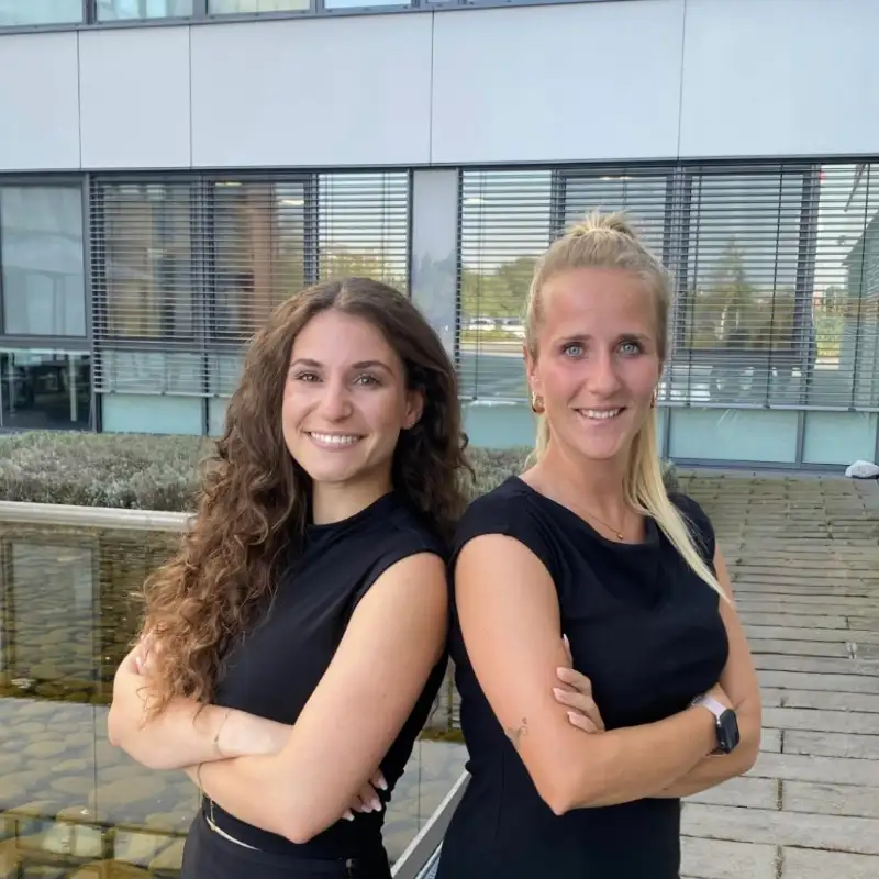 Fabienne Delp und Selina Rettig, Mitarbeiterinnen bei Transgourmet stehen auf dem Hof vor ihrem Bürogebäude.