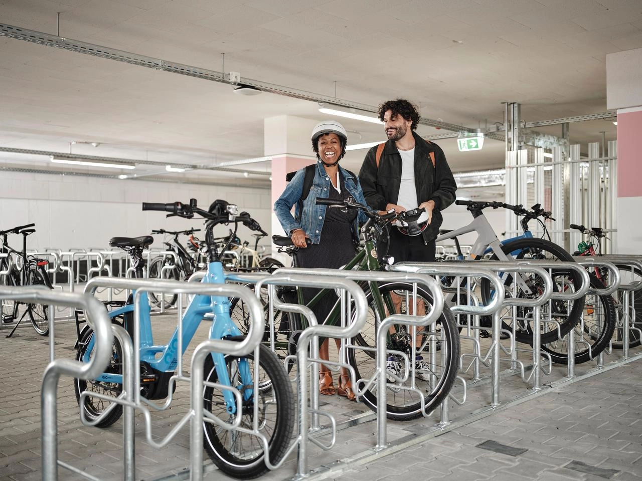 Zwei JobRadler:innen steigen aufs Fahrrad im Fahrradkeller.